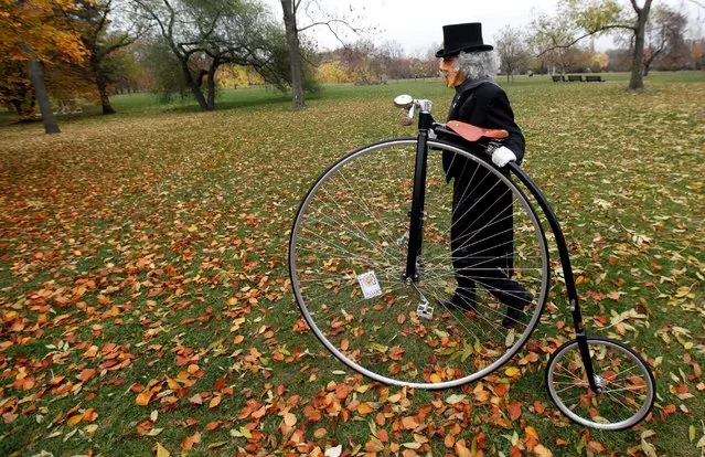 A woman wearing a historical costume and a mask pushes her high-wheel bicycle before the annual penny farthing race in Prague, Czech Republic November 5, 2016. (Photo by David W. Cerny/Reuters)