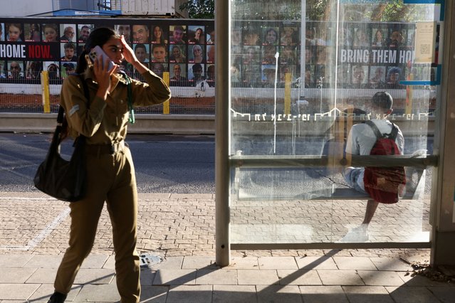 People wait for a bus near images of those taken hostage or killed during the deadly October 7 attack, amid the ongoing conflict in Gaza between Israel and Hamas, in Tel Aviv, Israel on September 17, 2024. (Photo by Jim Urquhart/Reuters)