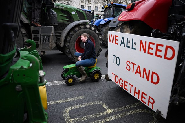 A demonstrator rides toy tractor past a placard reading “We all need to stand together” and down Whitehall during a stop “the death of British Farming” demonstration, to protest against changes to inheritance tax rules for land ownership for farmers, in central London, on December 11, 2024. (Photo by Oli Scarff/AFP Photo)