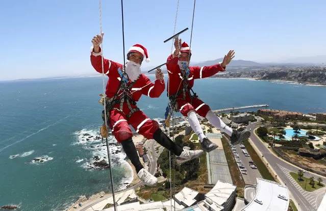 Workers wave as they clean the windows of a building, dressed as Santa Claus, in Vina del Mar city Chile December 23, 2015. (Photo by Rodrigo Garrido/Reuters)