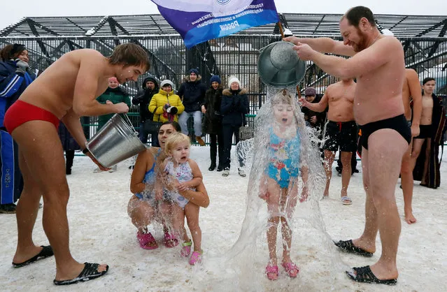 Visitors watch as members of a local winter swimmers club pour buckets of cold water over their daughters, 7-year-old Liza Broverman and 2-year-old Alisa Smagina during a celebration of Polar Bear Day at the Royev Ruchey zoo, with the air temperature at about minus 5 degrees Celsius (23 degrees Fahrenheit), in Krasnoyarsk, Russia, November 27, 2016. (Photo by Ilya Naymushin/Reuters)