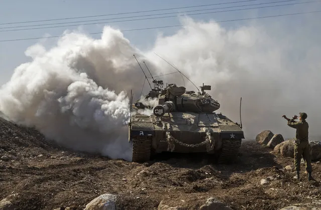 An Israeli soldier directs a Merkava tank near the border with Syria in the Israeli-annexed Golan Heights, on November 28, 2016. Israel's air force targeted gunman linked to the Islamic State group in Syria overnight, the army said, after they fired on an Israeli soldier in the occupied Golan Heights. (Photo by Jack Guez/AFP Photo)