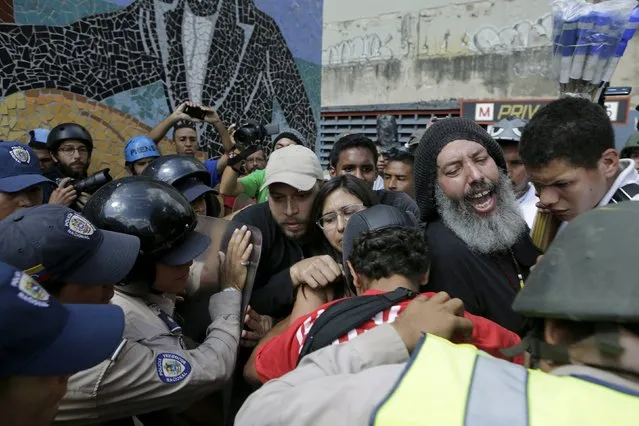 Policemen contain supporters of Venezuela's President Nicolas Maduro as they try to approach to opposition supporters some streets away from the building housing the National Assembly in Caracas, January 5, 2016. (Photo by Marco Bello/Reuters)