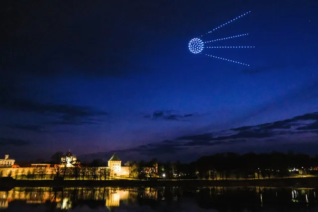 Drones forming a figure of the first artificial Earth satellite “Sputnik 1” light up the evening sky on the eve of Cosmonautics Day in Veliky Novgorod, Russia on April 11, 2021. (Photo by Press service of the Government of the Novgorod region/Handout via Reuters)