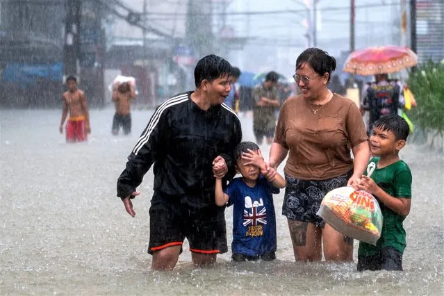 People wade through a flooded road, due to monsoon rains and the recent typhoon Doksuri, in Balagtas, Bulacan province, Philippines on July 29, 2023. (Photo by Lisa Marie David/Reuters)