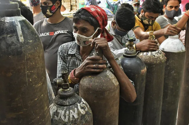 Indians wait to refill oxygen cylinders for COVID-19 patients at a gas supplier facility in New Delhi, India, Saturday, May 8, 2021. Infections have swelled in India since February in a disastrous turn blamed on more contagious variants as well as government decisions to allow massive crowds to gather for religious festivals and political rallies. (Photo by Ishant Chauhan/AP Photo)
