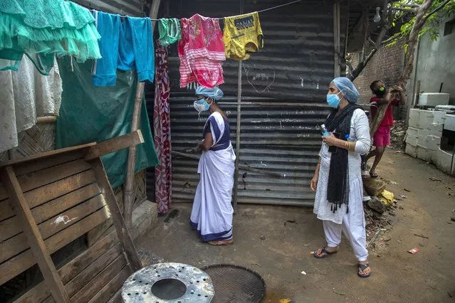 Heath workers call a woman, unseen, who does not agree to give swab sample to test for COVID-19 in a slum in Gauhati, Assam, India, Monday, May 17, 2021. (Photo by Anupam Nath/AP Photo)