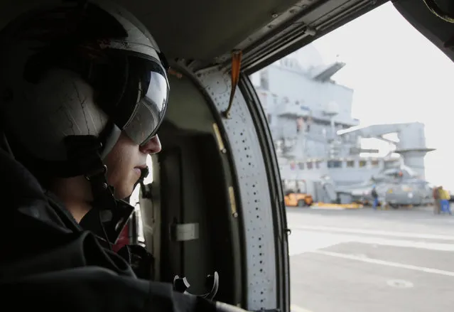 A U.S. military officer looks out at the flight deck of the French navy aircraft carrier Charles de Gaulle in the Persian Gulf as the U.S. helicopter prepares for takeoff Thursday, March 19, 2015. (Photo by Hasan Jamali/AP Photo)