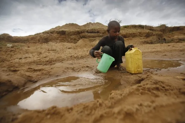 A young boy scoops water from a hand-dug well in the dry riverbed near Matinyani, in the semi-arid Kitui County in southeastern Kenya, 22 March 2015, the World Water Day. Residents of Kitui County and other arid and semi-arid areas of the country have been hard-hit by extremely poor rainfall this year while the government said in previous month that some 1.6 million people countrywide are facing acute starvation due to the drought and will need relief food over the next six months. (Photo by Dai Kurokawa/EPA)