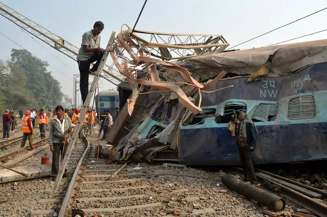 A man cuts an iron frame in front of a damaged coach of a passenger train after it derailed near Kanpur in the northern state of Uttar Pradesh, India, December 28, 2016. (Photo by Reuters/Stringer)