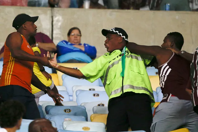 A security guard, center, separates two fans of Brazil's Fluminense who face at the end of a Copa Sudamericana second leg semifinal match against Brazil's Atletico Paranaense at the Maracana stadium in Rio de Janeiro, Brazil, Wednesday, November 28, 2018. Atletico Paranaense won 4-0 and qualified for the final. (Photo by Leo Correa/AP Photo)