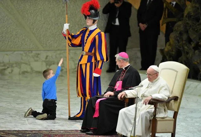 A child comes close to Pope Francis, right, as he leads the weekly general audience at the Paul VI Audience Hall in Vatican City on November 28, 2018. (Photo by Evandro Inetti/ZUMA Wire/Rex Features/Shutterstock)