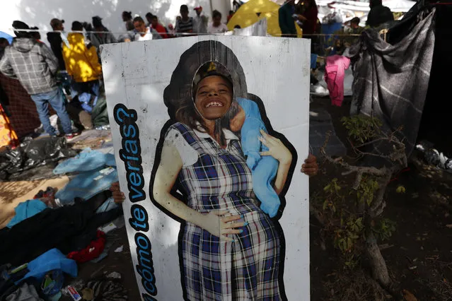 A boy plays with a life-size cardboard cutout of a pregnant woman at the Benito Juarez sports complex, in Tijuana, Mexico, on Friday, November 30, 2018. Authorities in the Mexican city of Tijuana have been transferring the more than 6,000 Central American migrants from an overcrowded shelter on the border to an events hall further away. (Photo by Rebecca Blackwell/AP Photo)