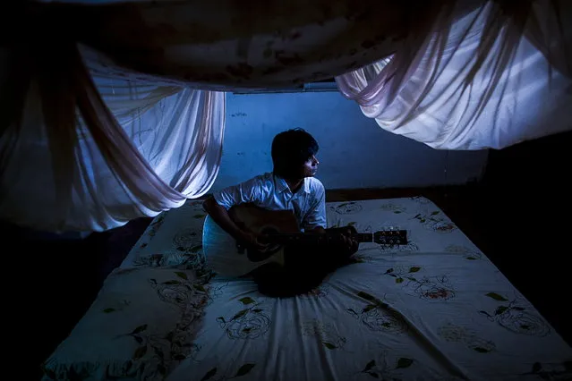 “Burma Spring”. Thirty year old Nlay chi win playing guitar at his secrect home in Rangoon, Burma. This place was not available for any strangers to visit before Burmese political reforms. Photo location: Rangoon, Burma. (Photo and caption by Jia Daitengfei/National Geographic Photo Contest)