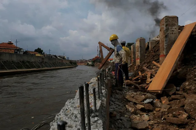 Workers are seen during the construction of the concrete walls to prevent flooding at the Ciliwung river bank at Jatinegara district in Jakarta, Indonesia, December 29, 2016. (Photo by Reuters/Beawiharta)