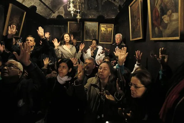 Christian worshippers pray inside inside the Grotto, where Christians believe Virgin Mary gave birth to Jesus, during Christmas celebrations at the Church of the Nativity in the West Bank town of Bethlehem December 24, 2013. (Photo by Ammar Awad/Reuters)