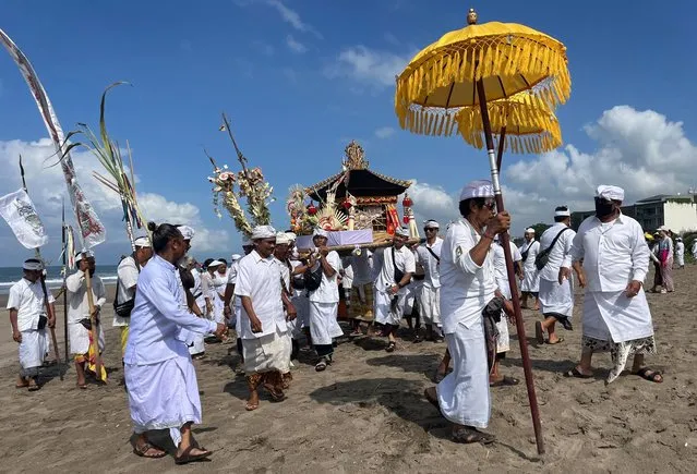 Members of the Hindu community take part in a ceremony marking the full moon in the Kerobokan district on the Indonesian resort island of Bali on December 28, 2023. (Photo by David Gannon/AFP Photo)