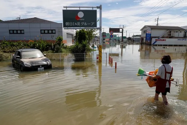 A woman carries her belongings through a flooded street in Takeo, Saga Prefecture, western Japan, August 15, 2021. (Photo by Kim Kyung-Hoon/Reuters)