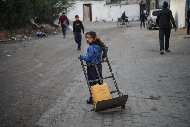 A Palestinian girl carries bottled water in a wheelbarrow while Israel's attacks continue on Gaza Strip as Palestinians who took refuge in the city of Rafah are trying to continue their daily work even though the attacks continue in Rafah, Gaza on January 03, 2024. Palestinian residents meet their water needs from mobile tanks and fountains in the region. Palestinian families are trying to survive under difficult conditions in makeshift tents. (Photo by Abed Zagout/Anadolu via Getty Images)