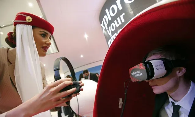 An Emirates Airlines flight attendant assists a visitor using a Gear VR virtual reality headset by Oculus and Samsung Electronics, at the Emirates Airlines exhibition stand during the International Tourism Trade Fair (ITB) in Berlin, Germany, March 9, 2016. (Photo by Fabrizio Bensch/Reuters)
