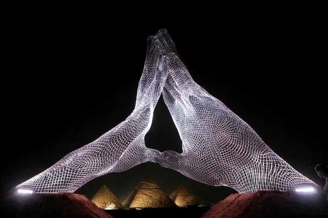 An installation by Italian artist Lorenzo Quinn, entitled “Together”, sits facing the pyramids at the ancient Giza necropolis on the western outskirts of the Egyptian capital's twin city of Giza, on October 23, 2021. Art D’Egypte launched its 4th annual exhibition entitled “Forever Is Now” 2021, the first international art exhibition to take place at the Giza Pyramids and the surrounding Giza Plateau. (Photo by Patrick Baz/Art Degypte/AFP Photo)