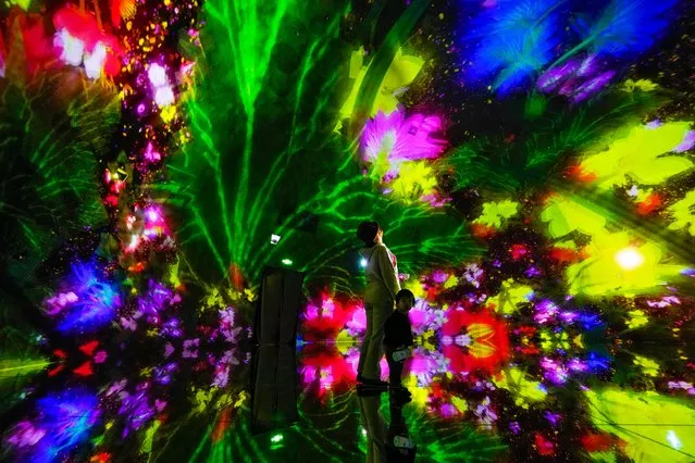 A woman and a child experience a digital installation that features projection of flowers titled “Floating in the Falling Universe of Flowers”, at the newly opened “teamLab Massless” museum in Beijing, Monday, December 26, 2022. The “teamLab Massless” by Tokyo-based art collective teamLab create the digital art museum showcasing various interactive artworks inside a shopping mall in the capital city of Beijing. (Photo by Andy Wong/AP Photo)