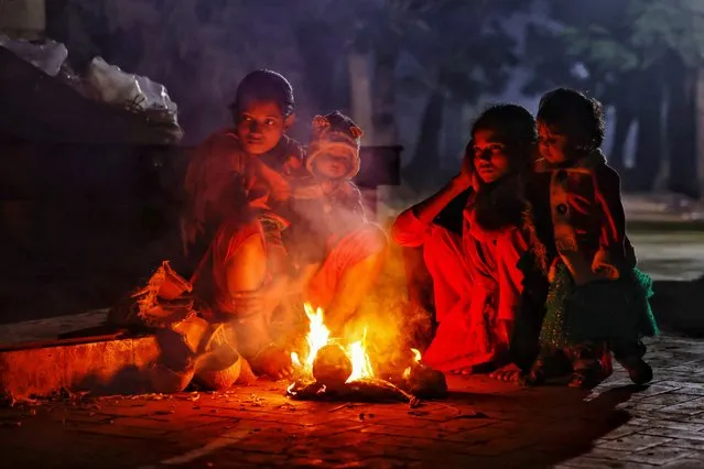 Homeless people who live at the Suhrawandy Udyan light a fire to warm themselves, as temperature drops significantly during winter in Dhaka, Bangladesh on January 17, 2024. (Photo by Mohammad Ponir Hossain/Reuters)