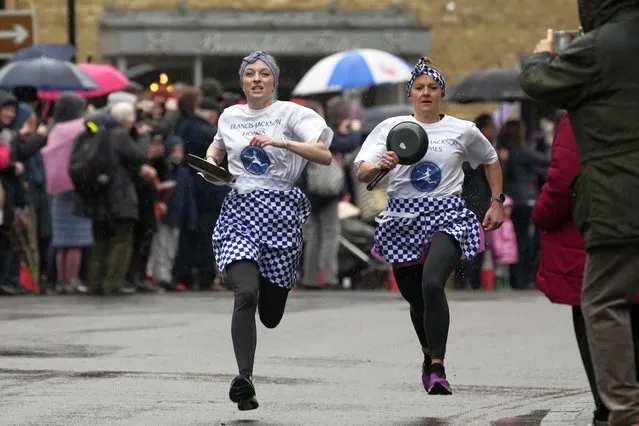 Pancake race winner Kaisa Larkas, right, and second place finisher Eloise Kramer run ahead during the annual Shrove Tuesday trans-Atlantic pancake race in the town of Olney, in Buckinghamshire, England, Tuesday, February 13, 2024. Every year women clad in aprons and head scarves from Olney and the city of Liberal, in Kansas, USA, run their respective legs of the race with pancakes in their pans. According to legend, the Olney race started in 1445 when a harried housewife arrived at church on Shrove Tuesday still clutching her frying pan with a pancake in it. (Photo by Kin Cheung/AP Photo)
