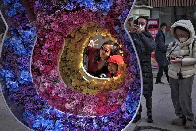 A woman and a child pose a souvenir photo with a rabbit shaped floral decoration at a pedestrian shopping street at Qianmen on the first day of the Lunar New Year holiday in Beijing, Sunday, January 22, 2023. People across China rang in the Lunar New Year on Sunday with large family gatherings and crowds visiting temples after the government lifted its strict “zero-COVID” policy, marking the biggest festive celebration since the pandemic began three years ago. (Photo by Andy Wong/AP Photo)