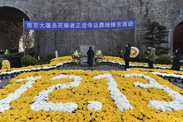 People wearing face masks hold flowers as they mourn for the victims of the Nanking Massacre at a mass burial site during the annual commemoration of the 1937 Nanking Massacre in Nanjing in eastern China's Jiangsu province, Monday, December 13, 2021. China on Monday marking the 84th anniversary of the Nanking Massacre, in which it says hundreds of thousands of civilians and disarmed soldiers were killed by Japanese soldiers in and around the former Chinese capital. (Photo by Chinatopix via AP Photo)