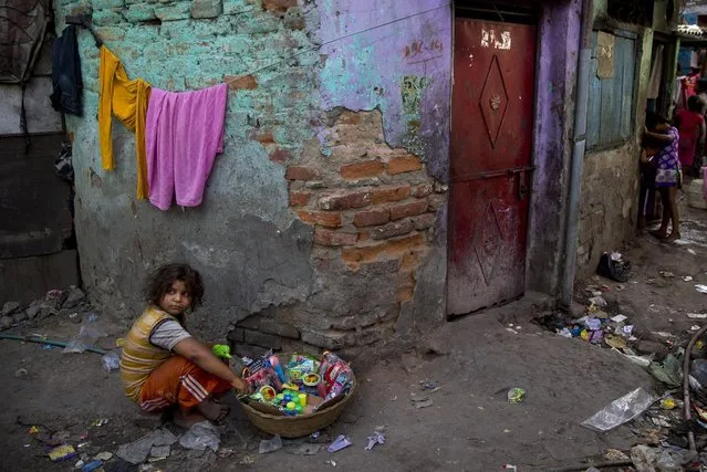An Indian girl waits for customers as she sells toys at a slum in New Delhi, India, Wednesday, May 20, 2015. A 2013 census report with India's first complete count of its vast slum population says one in six people in Indian cities live in some 100,000 sprawling slums with conditions “unfit for human habitation”. (Photo by Saurabh Das/AP Photo)