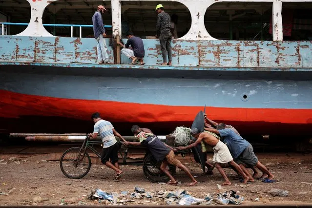 Bangladeshi labourers pull a cart carrying a ferry propeller in a dockyard in Dhaka, Bangladesh on March 27, 2024. (Photo by Mohammad Ponir Hossain/Reuters)