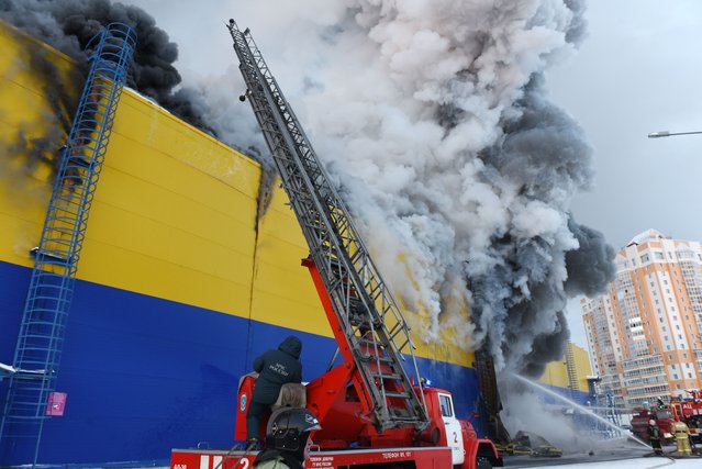 Firefighters battle a fire at a Lenta hypermarket in the city of Tomsk, Russia on December 21, 2021. (Photo by Taisiya Vorontsova/TASS)