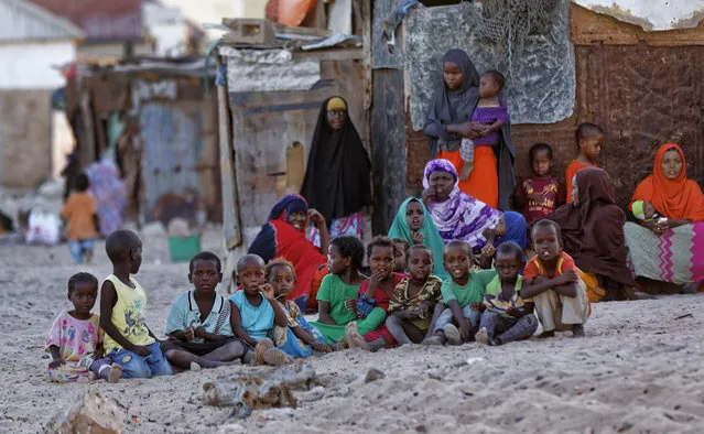 Somali women and children gather at dusk on a sandy street in the former pirate village of Eyl, in Somalia's northeastern semiautonomous state of Puntland, Monday, March 6, 2017. (Photo by Ben Curtis/AP Photo)