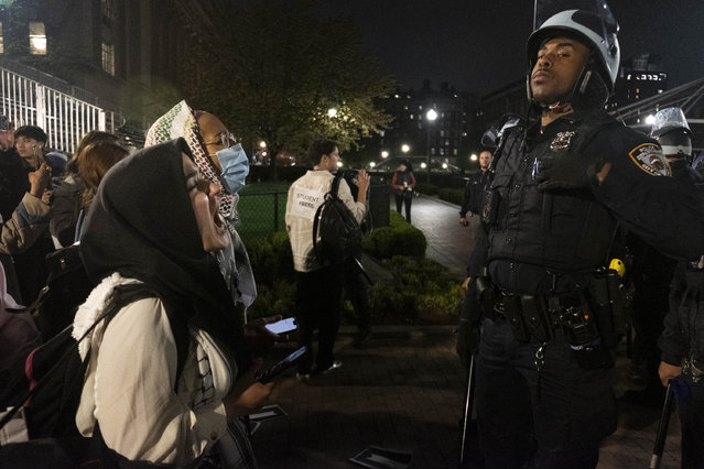 Pro-Palestine student activists face off with New York Police Department officers during a raid on Columbia University's campus at the request of Columbia University President Minouche Shafik on Tuesday evening, April 30, 2024 in New York. NYPD officers, including those from the police department's Strategic Response Group, arrested approximately 100 people as they dismantled encampments and removed individuals occupying Hamilton Hall. (Photo by Seyma Bayram via AP Photo)