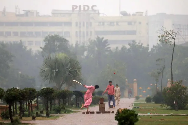 Boys play cricket amid rain at a park in Karachi, Pakistan on December 27, 2021. (Photo by Akhtar Soomro/Reuters)