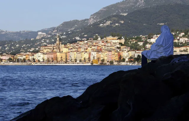 A migrant sits on the rocks of the seawall at the Saint Ludovic border crossing on the Mediterranean Sea between Vintimille, Italy and Menton, France, June 17, 2015. Police on Tuesday began hauling away mostly African migrants from makeshift camps on the Italy-France border as European Union ministers met in Luxembourg to hash out plans to deal with the immigration crisis. The French city of menton is seen in the background.      REUTERS/Eric Gaillard  