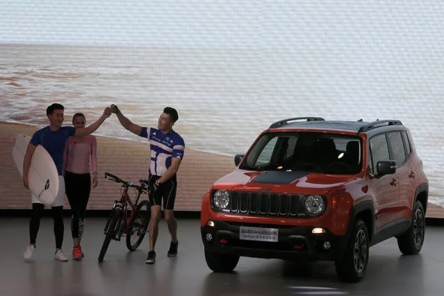Performers take part in a presentation next to the new Jeep Renegade model after it was unveiled at the Beijing International Automotive Exhibition in Beijing, Monday, April 25, 2016. (Photo by Andy Wong/AP Photo)