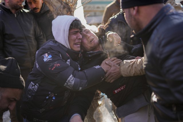 The son of Turkish Durmus Kilinc, center, reacts after rescue team members removed the dead body of his father from a destroyed building, in Elbistan, southeastern Turkey, Thursday, February 9, 2023. Tens of thousands of people who lost their homes in a catastrophic earthquake huddled around campfires in the bitter cold and clamored for food and water Thursday, three days after the temblor hit Turkey and Syria. (Photo by Francisco Seco/AP Photo)