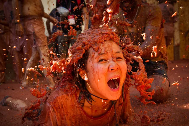 A reveller covered in tomato pulp participates in the annual “Tomatina” festival in the eastern town of Bunol, on August 28, 2019. The iconic fiesta, which is billed at “the world's biggest food fight” has become a major draw for foreigners, in particular from Britain, Japan and the United States. (Photo by Jaime Reina/AFP Photo)