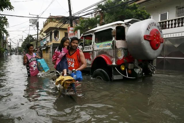 A father holds his daughter standing on the handle bars of their bicycle, as they wade through waist-deep flooding caused by typhoon Linfa, locally named Egay, at Longos town in Malabon city, north of Manila July 6, 2015. (Photo by Romeo Ranoco/Reuters)
