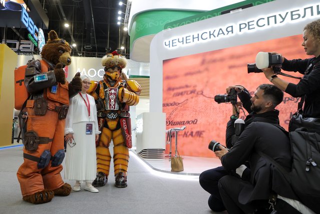 A visitor poses for a picture with participants wearing costumes depicting animated characters at the St. Petersburg International Economic Forum (SPIEF) in Saint Petersburg, Russia on June 5, 2024. (Photo by Anton Vaganov/Reuters)