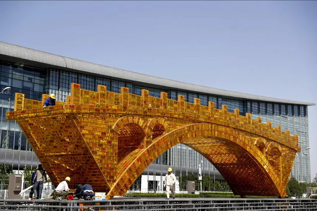 Workers install wires on a “Golden Bridge of Silk Road” structure on a platform outside the National Convention Center, the venue which will hold the Belt and Road Forum for International Cooperation, in Beijing, April 18, 2017. Leaders of 28 countries are set to attend the Chinese summit showcasing President Xi Jinping's signature foreign policy plan, but few will hail from major Western countries. Chinese foreign minister Wang Yi said Tuesday that Vladmir Putin of Russia, Recep Tayyip Erdogan of Turkey and Spain's Mariano Rajoy are among those slated to appear next month in Beijing for a summit to discuss Xi's “One Belt, One Road” infrastructure investment program to stitch together the Eurasian continent. (Photo by Andy Wong/AP Photo)