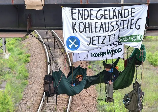 Environmental activists of environmantal organization “Robin Wood” lie in hammocks over tracks leading to the coal-fired power station Schwarze Pumpe belonging to Swedish state-owned energy giant Vattenfall, in Schwarze Pumpe, eastern Germany, on May 15, 2016 during anti-coal demonstrations. The protests are part of the “Break Free” campaign launched by Greenpeace and other environmentalist groups in countries including the US, Canada and Brazil to oppose the use of fossil fuels. (Photo by Patrick Pleul/AFP Photo/DPA)