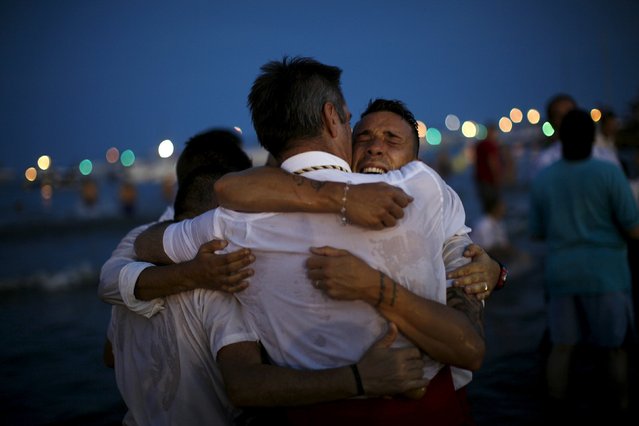 Men in traditional costumes embrace after carrying a statue of the El Carmen Virgin into the sea during a procession in Malaga July 16, 2015. (Photo by Jon Nazca/Reuters)