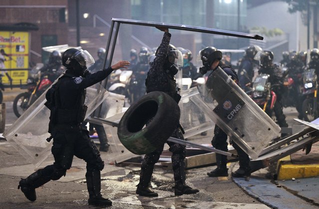 Police officers remove debris during a protest against Venezuelan President Nicolas Maduro's government in Caracas on July 29, 2024, a day after the Venezuelan presidential election. Protests erupted in parts of Caracas Monday against the re-election victory claimed by Venezuelan President Nicolas Maduro but disputed by the opposition and questioned internationally, AFP journalists observed. (Photo by Yuri Cortéz/AFP Photo)