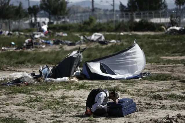 A Kurdish man sits on the ground as he waits to leave a makeshift camp during a police operation at the Greek-Macedonian border near the northern Greek village of Idomeni, Thursday, May 26, 2016. Greek police continue to evacuate the sprawling, makeshift Idomeni refugee camp where more than an estimated 8,400 people have been living for months. (Photo by Yannis Kolesidis/ANA-MPA via AP Photo)