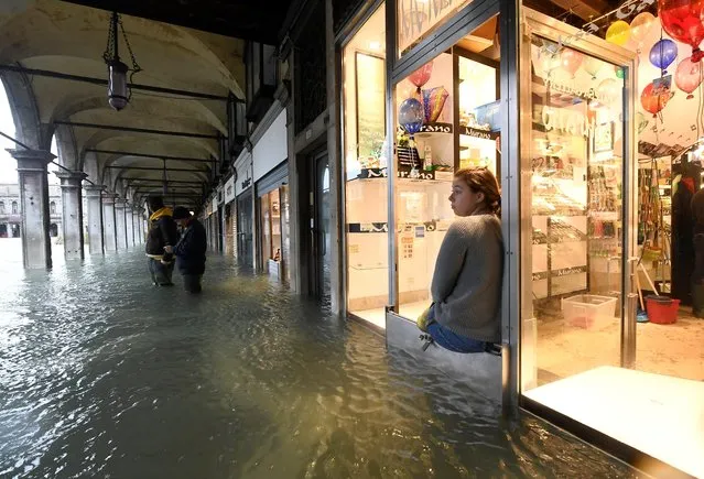 A woman looks on from a shop at the flooded St. Mark's Square, as high tide reaches peak, in Venice, November 15, 2019. The Italian city has declared a state of emergency after “apocalyptic” floods swept through the lagoon city, flooding its historic basilica and inundating squares and centuries-old buildings. (Photo by Flavio Lo Scalzo/Reuters)