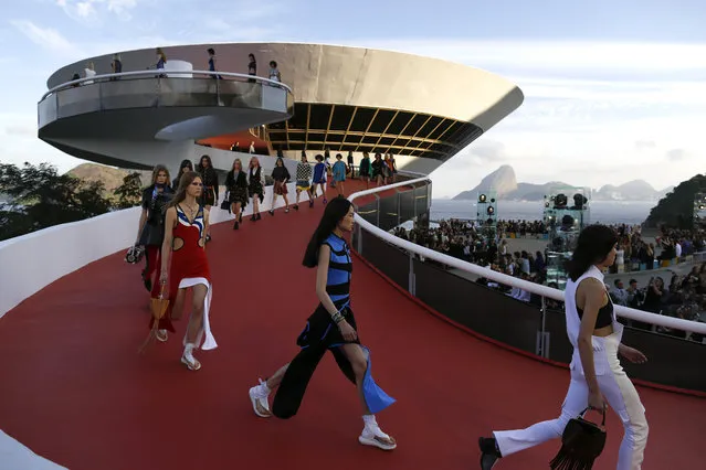 Models walk down a ramp of the Contemporary Art Museum wearing creations from the Louis Vuitton Crusie 2017 collection, in Niteroi, Brazil, Saturday, May 28, 2016. The elite of the fashion world flocked to Brazil, defying an outbreak of the Zika virus, an economic meltdown and the profound political crisis afflicting the country to attend a runway show Saturday by revered French label. The iconic Sugarloaf Mountain is pictured in the background on right. (Photo by Leo Correa/AP Photo)