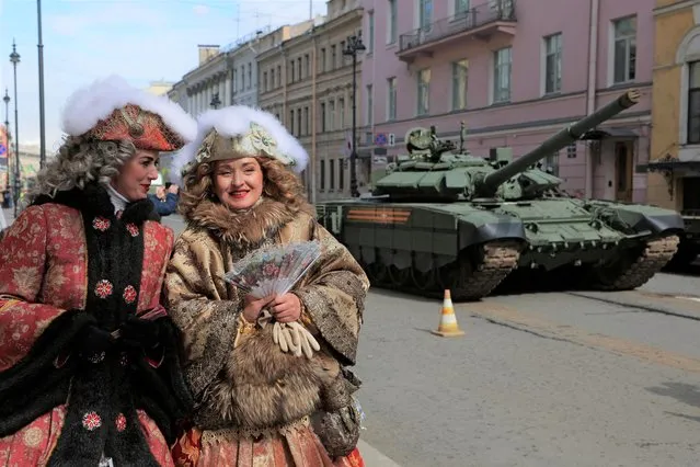 Women wearing historical costumes walk past a tank before a rehearsal for the Victory Day parade, which marks the anniversary of the victory over Nazi Germany in World War Two, in Saint Petersburg, Russia on April 28, 2022. (Photo by Anton Vaganov/Reuters)